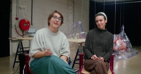 Two women sitting in front of a table.