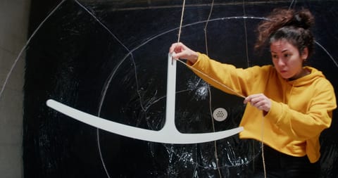 Woman holding string to draw on blackboard