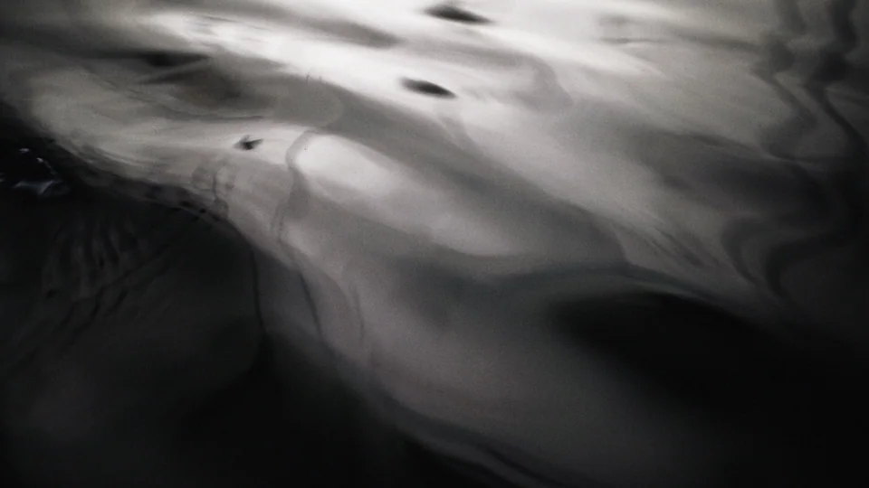 This is a blurry image with dark and light swirls, evoking the impression of water.