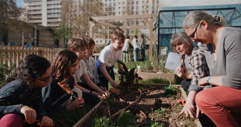 Children in a garden learning from woman.