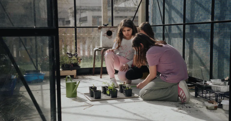 Two people in a greenhouse setting, looking at plants.