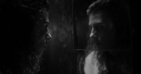 A dark scene from a film with two people.