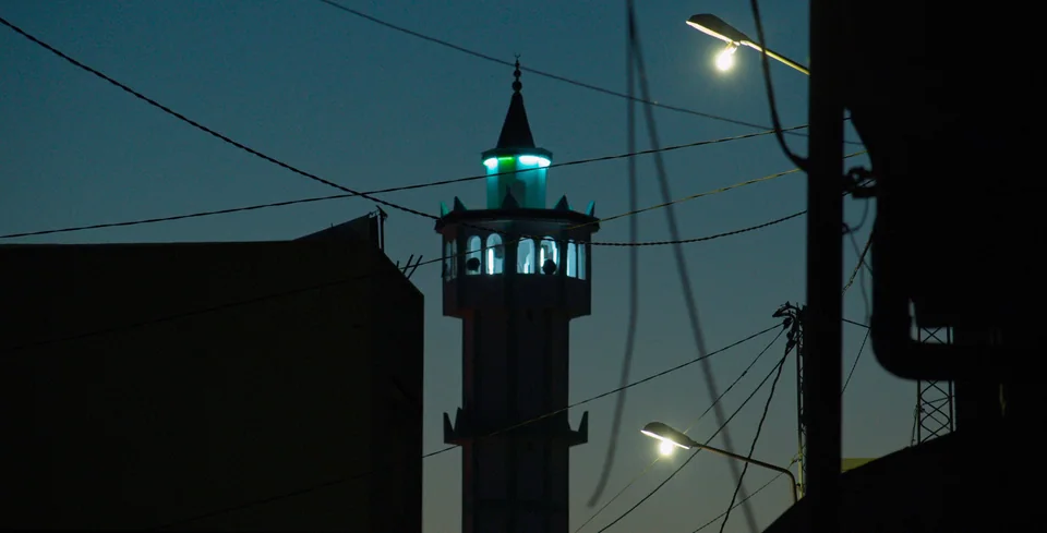 Minaret lit up against night sky.
