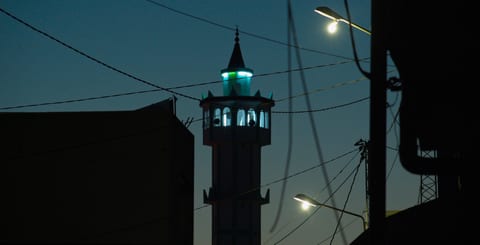 Minaret lit up against night sky.