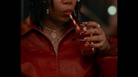 A person in a red top drinking from a clear plastic cup.