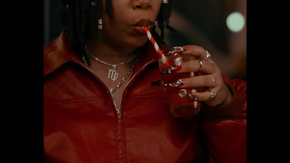 A person in a red top drinking from a clear plastic cup.
